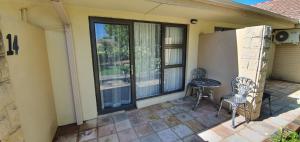 a patio with a table and chairs and a window at Acacia Lodge in Bloemfontein