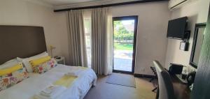 een slaapkamer met een bed en een groot raam bij Acacia Lodge in Bloemfontein