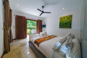 a bedroom with a bed and a ceiling fan at Villa Collard in Senggigi