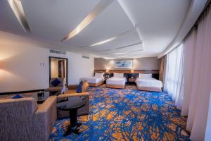 a hotel room with two beds and a living room at Al Ghufran Safwah Hotel Makkah in Mecca