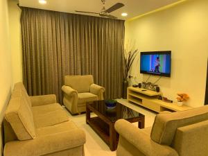 a living room with two chairs and a flat screen tv at Areia De Goa, Comfort Stay Apartment near Baga Beach in Baga