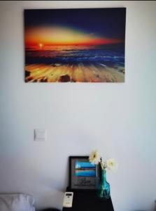a painting hanging on a wall above a desk with a laptop at Milos Lifestyle Villa 17 in Protaras