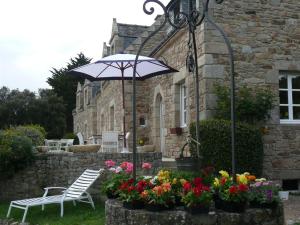 un jardín con banco, sombrilla y flores en Chambres d'hotes "Manoir Des Quatre Saisons", en La Turballe