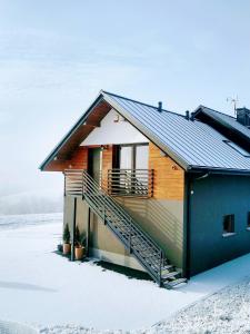 a house with a staircase in the snow at Apartament Bukowinka in Krośnica