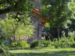 un jardin avec des fleurs et des arbres et un bâtiment dans l'établissement Chambres d'hôtes-Les Chambres de Mado, à Margencel