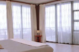 a bedroom with large windows with a bed and a table at 4 Bedroom Luxury Home with View of the Ocean and Table Mountain in Cape Town +8 photos