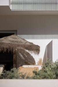 
a large umbrella sitting under a tree in front of a building at The Olive - Boutique Apartment Hotel and Spa in Cala Llonga
