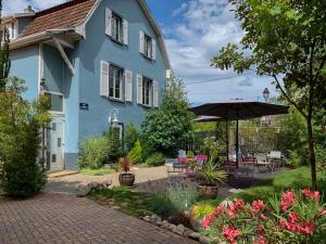 ein blaues Haus mit einem Sonnenschirm und einer Terrasse in der Unterkunft Chambres d'Hôtes Le Domaine des Remparts in Sélestat