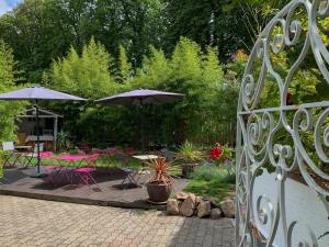 een patio met tafels, stoelen en parasols bij Chambres d'Hôtes Le Domaine des Remparts in Sélestat