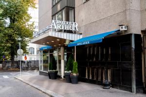 uma loja na frente de um edifício com um guarda-chuva azul em Hotel Arthur em Helsinque