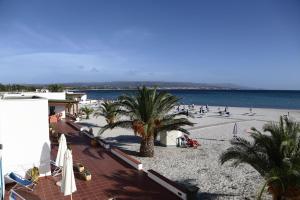 una spiaggia con palme e persone sulla spiaggia di Vel Marì - Rooms on the Beach ad Alghero