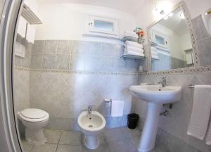 bagno con lavandino, servizi igienici e specchio di Vel Marì - Rooms on the Beach ad Alghero