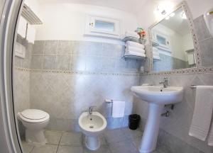 een badkamer met een wastafel, een toilet en een spiegel bij Vel Marì - Rooms on the Beach in Alghero +37 foto's