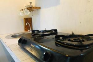 a stove top in a kitchen with a sink at Rascal House Gili Trawangan in Gili Trawangan