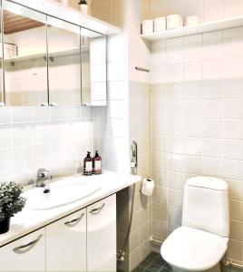 a white bathroom with a toilet and a sink at City Home Finland Tampella - City View, Own SAUNA, One Bedroom, Furnished Balcony and Great Location in Tampere