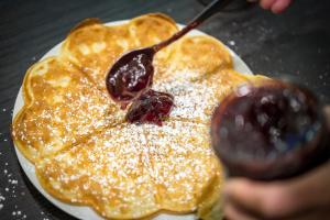 a person is spreading syrup on a plate with pancakes at Hotel Im Schulhaus in Lorch am Rhein