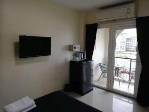 a room with a television on the wall with a balcony at Dania in Pattaya Central