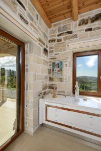 a bathroom with a stone wall and a window at Villa Agapi - sea view - ecological swimming pool - privacy in Lístaros