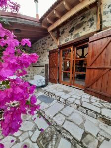 a stone patio with a wooden door and purple flowers at Blue Cottage in Apsiou