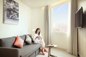 a woman sitting on a couch in a living room at HARRIS Hotel & Conventions Bundaran Satelit Surabaya in Surabaya