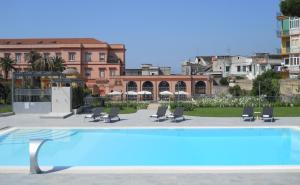 uma vista para uma piscina com cadeiras e guarda-sóis em Miglio d'Oro Park Hotel em Ercolano