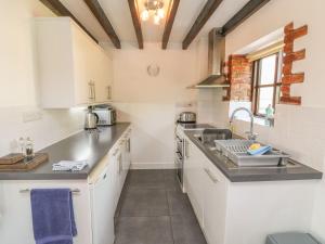 a kitchen with white cabinets and a sink at Stable Cottage in Colyton