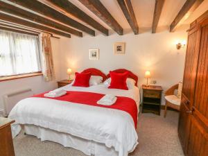 a bedroom with a large bed with red pillows at Coach Cottage in Colyton