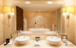 a bathroom with a tub, sink and mirror at InterContinental Lisbon, an IHG Hotel in Lisbon