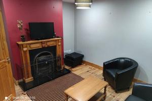 sala de estar con chimenea y TV en Townhouse 3 Barrow Lane, en Bagenalstown