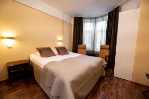 una camera da letto con un grande letto bianco con due cuscini di Hotel Arthur a Helsinki