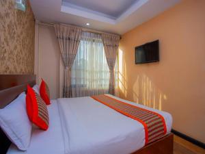 a bedroom with a bed with red pillows and a television at Yellow Pagoda Hotel in Kathmandu