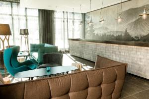 a living room filled with furniture and a large window at Motel One Freiburg in Freiburg im Breisgau