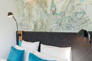 a room with a bed and a painting on the wall at Motel One Freiburg in Freiburg im Breisgau