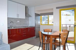 una cucina con armadi rossi e tavolo e sedie in legno di Rocha Apartment 1016 a Portimão