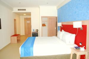 una camera con un grande letto con una parete rossa e blu di Best Western Plus Atlantic Hotel a Sekondi-Takoradi