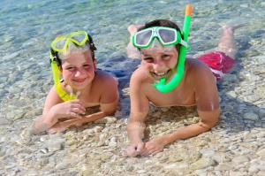 two people laying on the beach in the water at Valamar Diamant Hotel in Poreč