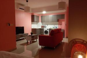 un soggiorno con sedia rossa e una cucina di HA213-Pool view Studio unit-Hyve-Cyberjaya- Free WiFi - Free parking-Netflix, 3020 a Cyberjaya