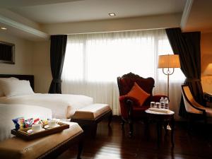 a hotel room with a bed and a chair at Gulliver's Tavern Hotel in Bangkok