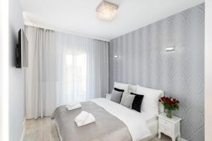 a white bedroom with a large bed with white pillows at Angel Apartments 1 in Krakow
