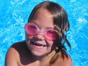 a young girl wearing a pair of goggles in a swimming pool at Apartmaji in sobe Kocjančič in Podčetrtek