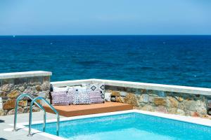 a swimming pool with a bench next to the ocean at Ethereal Villa in Panormos Rethymno