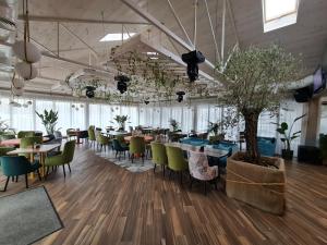 SPA Hotel Galera في كييف: غرفة طعام بها طاولات وكراسي وشجرة