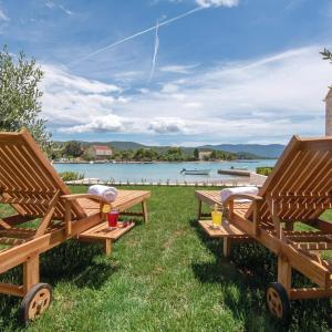two wooden benches sitting on the grass near the water at Holiday Home Lovište in Lovište