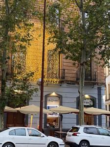 dos coches estacionados frente a un edificio con sombrillas en Apartamentos Reyes Catolicos 14 en Sevilla