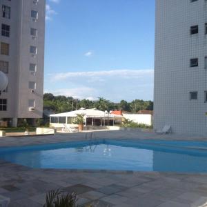 ein großer Pool zwischen zwei hohen Gebäuden in der Unterkunft Apartamento com piscina 1 quarto de até 6 pessoas - Guarujá in Guarujá