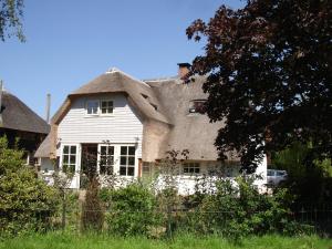 een groot wit huis met een rieten dak bij Cornucopia Cottage in Ingen