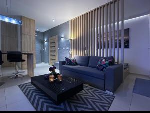 ein Wohnzimmer mit einem blauen Sofa und einem Tisch in der Unterkunft 4UApart-Apartment studio Platan New York in Świnoujście
