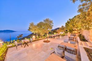 a patio with tables and chairs next to the water at Hamarat Otel in Kaş