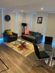 a living room with a couch and chairs and a clock at HIGH VIEW TWO BEDROOM APARTMENT IN WOOLWICH in London