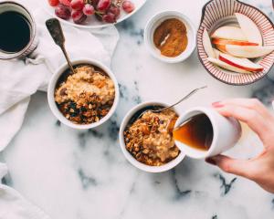 a person holding a cup of coffee next to bowls of food at Hotel Argento in St Julian's